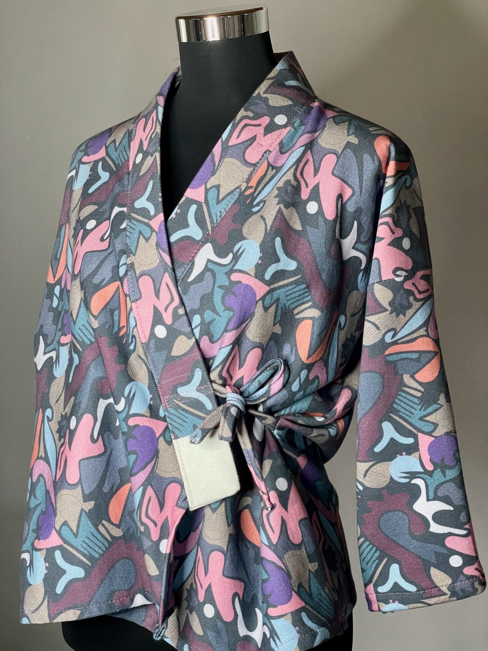 img 0870 Une veste pour femme avec un imprimé coloré, nouée avec des lanières. Parfaite pour ajouter une touche de style à votre tenue ! Motif Graffiti multicolore