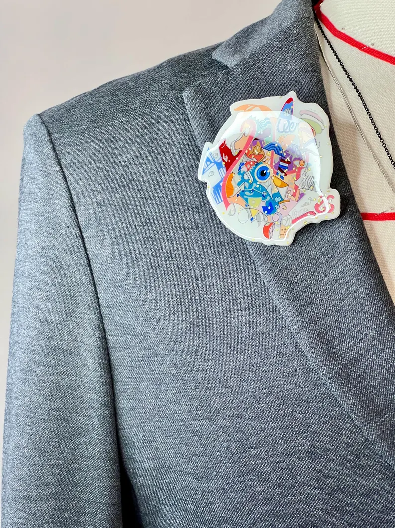 il 794xn.7066148385 3k4w.jpg Broche graffiti colorée inspirée de Paris 2024, épinglée au col d’un costume gris sur un mannequin de couture masculin. Création buuBoo.