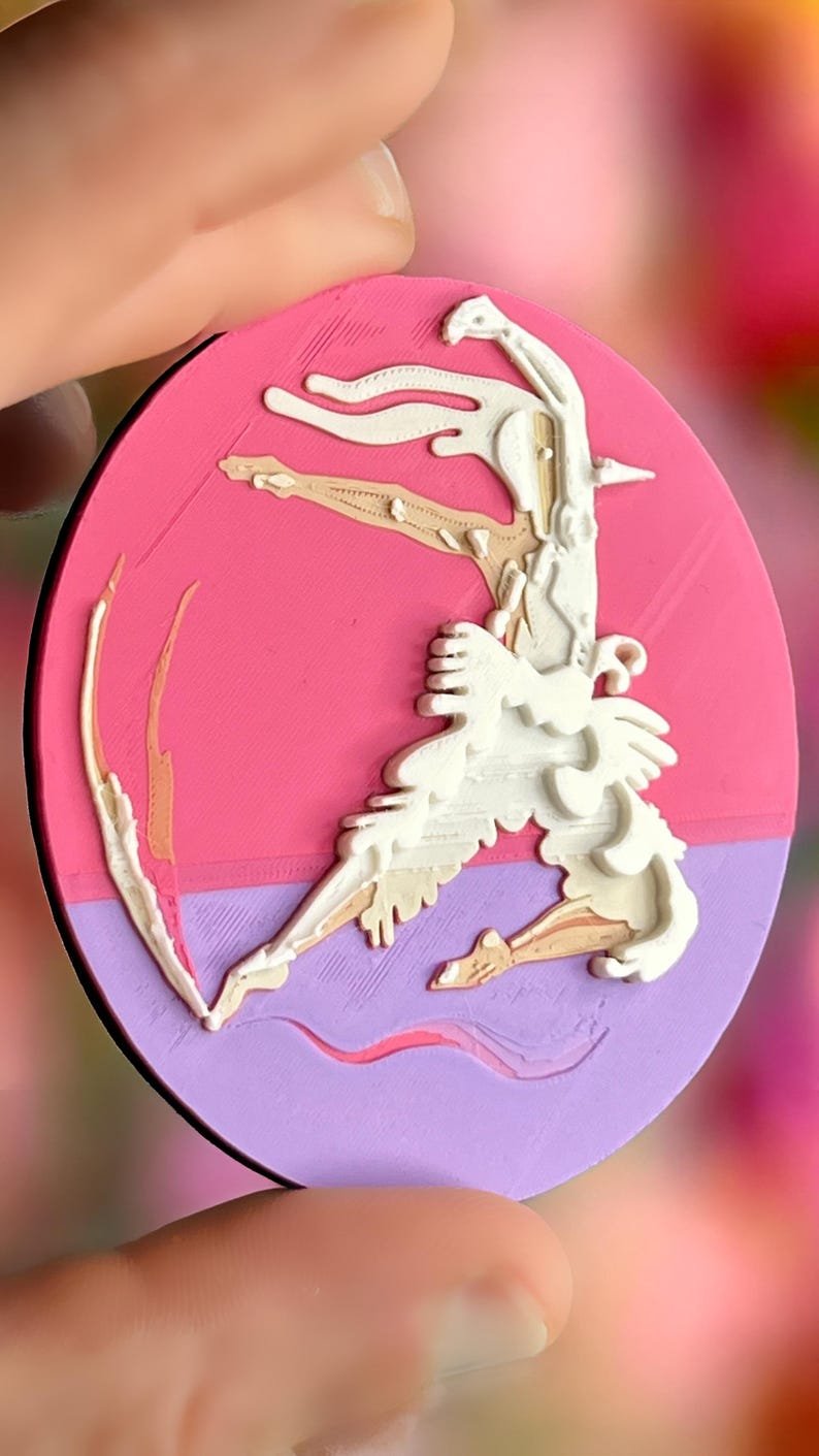 il 794xn.8344018469 7s7z Broche ronde Danseur-Cygne en relief imprimée en 3D, création originale aux tons magenta, mauve, beige et blanc, présentée en main. Marque buuBoo.