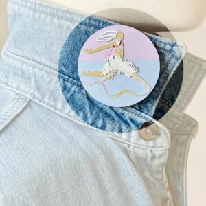 Broche Danseur-Cygne pastel portée sur le col d'une chemise, accessoire de vêtement imprimé en 3D aux nuances douces de rose, bleu, beige et blanc. Marque buuBoo.